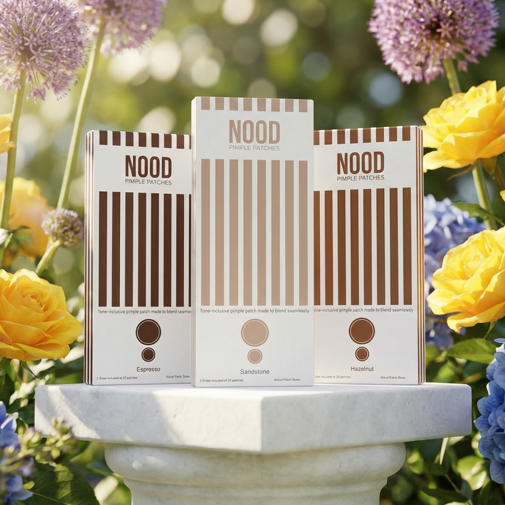 Three Nood Pimple Patch boxes on a pedestal with flowers in the background